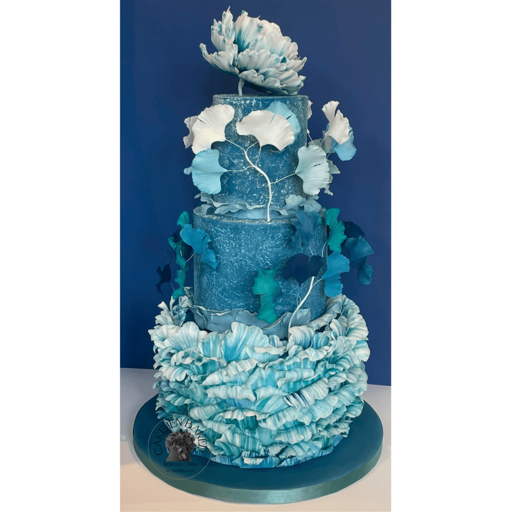 Three tier sugar paste cake decorated to the theme shades of the coast. Based on the ocean waves with a peony and ginkgo