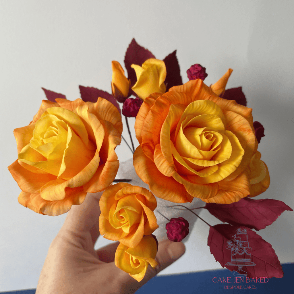 Autumnal sugar roses in shades of orange and yellow with burgundy foliage 