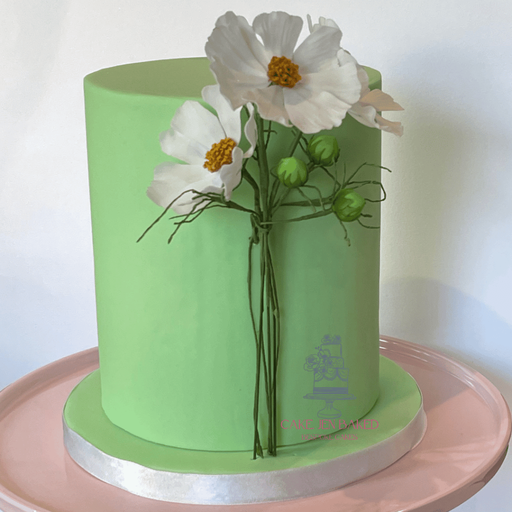 Single tier green cake with white sugar cosmos. This would be a perfect birthday cake, simple and elegant