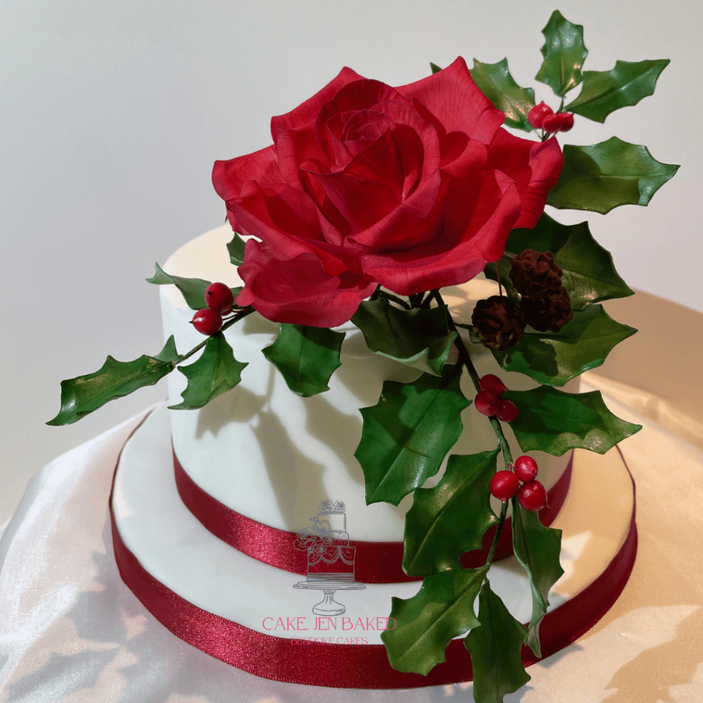 Christmas cake with a traditional theme. Red sugar rose with sugar holly and berries