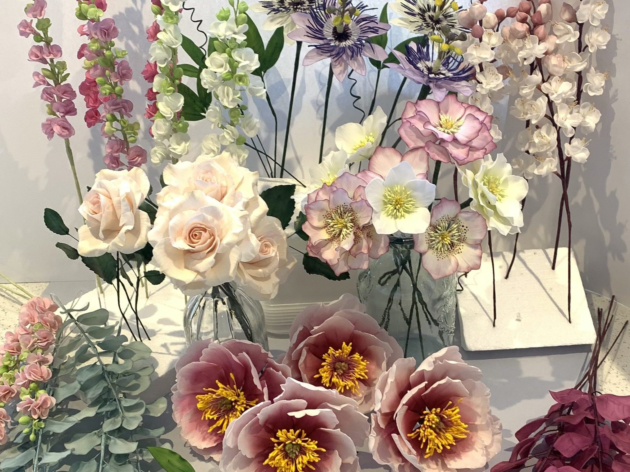 Selection of sugar flowers for wedding cakes. Includes sugar roses, sugar peonies, sugar cherry blossom, sugar passion flowers, sugar stocks, sugar eucalyptus, sugar smoke bush
